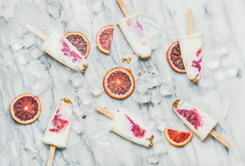 Blood orange, yogurt and granola popsicles on ice cubes